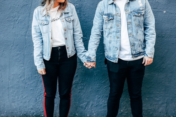 兩個人站在藍色的牆壁旁邊，手牽著手